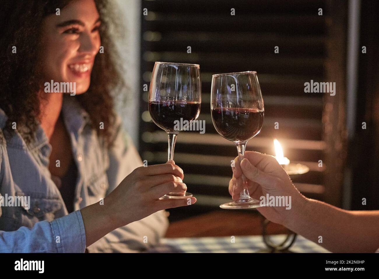 Prost zu uns. Aufnahme eines glücklichen jungen Paares, das beim Abendessen in die Gläser klirrend. Stockfoto