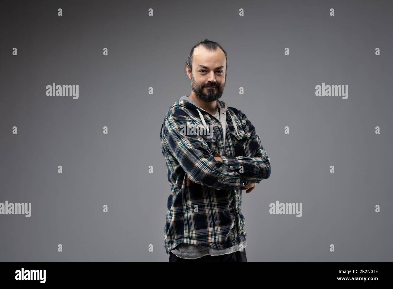 Halbdrehungsbild eines bärtigen Mannes mit zusammengeklappten Armen Stockfoto