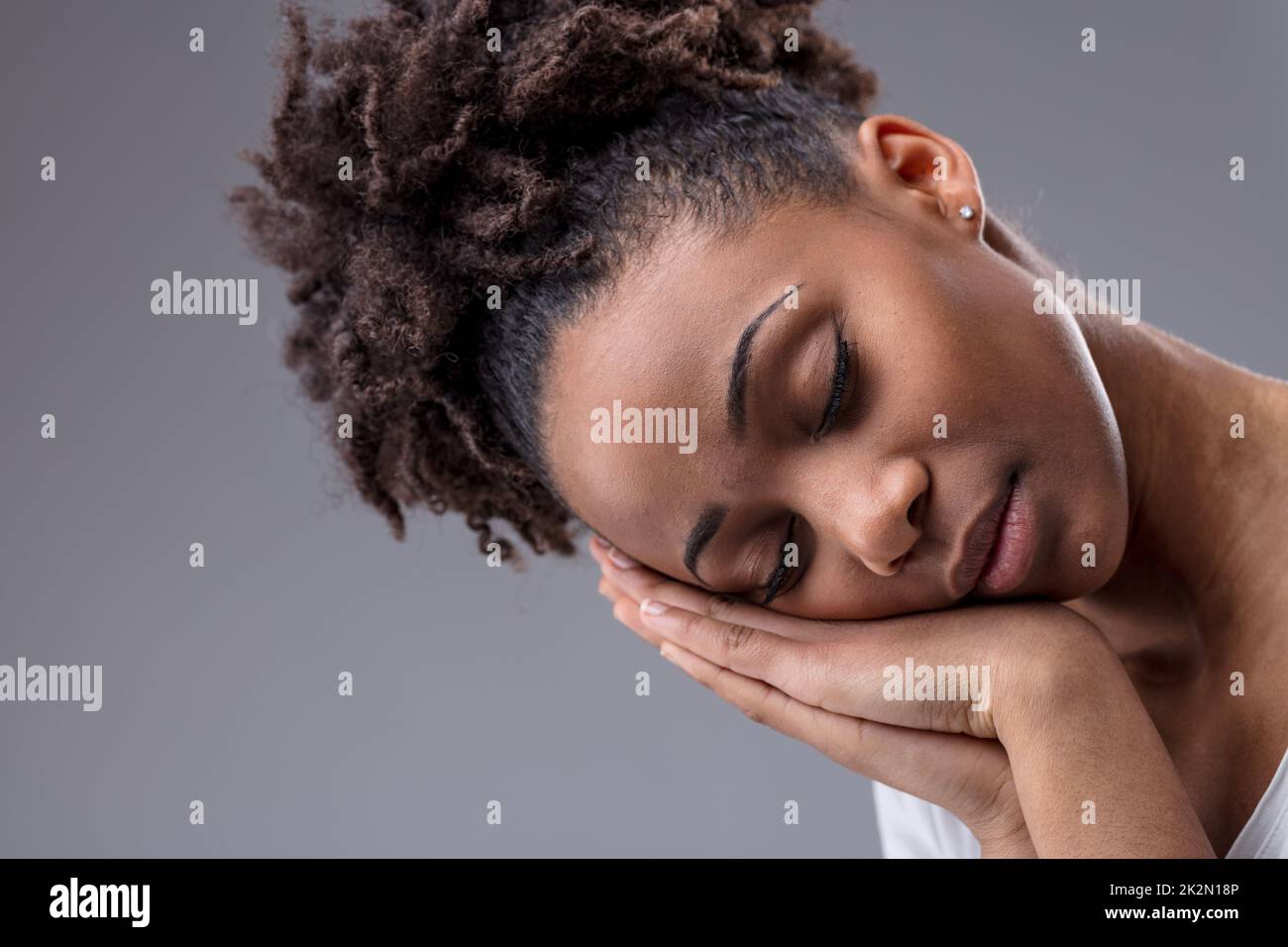 Müde, junge Frau, die mit Kopf auf den Händen schläft Stockfoto