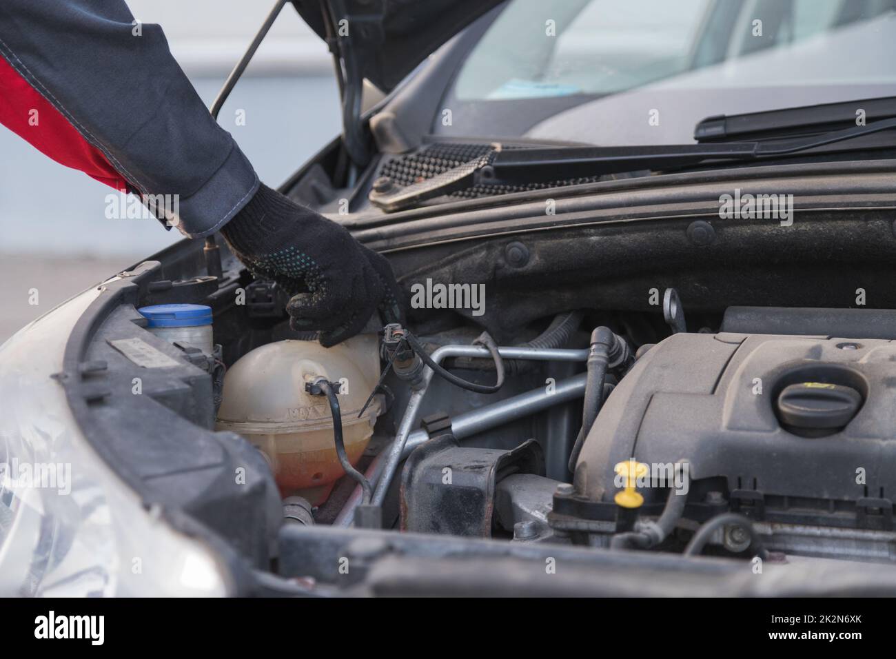 Auto Mechaniker entschrauben Expansion Tank Kappe zu Frostschutzmittel in Auto-Service-Werkstatt gießen Stockfoto