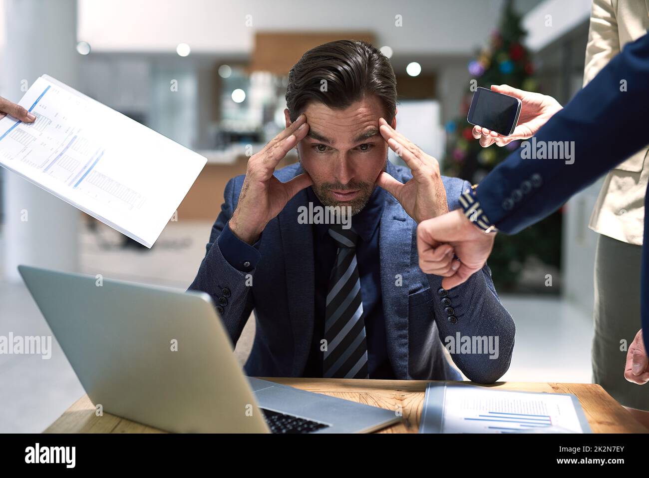 Die Anforderungen an die Arbeit können stressig sein. Aufnahme eines gestressten Geschäftsmannes, der an seinem Schreibtisch sitzt und von den Arbeitsanforderungen überwältigt ist. Stockfoto