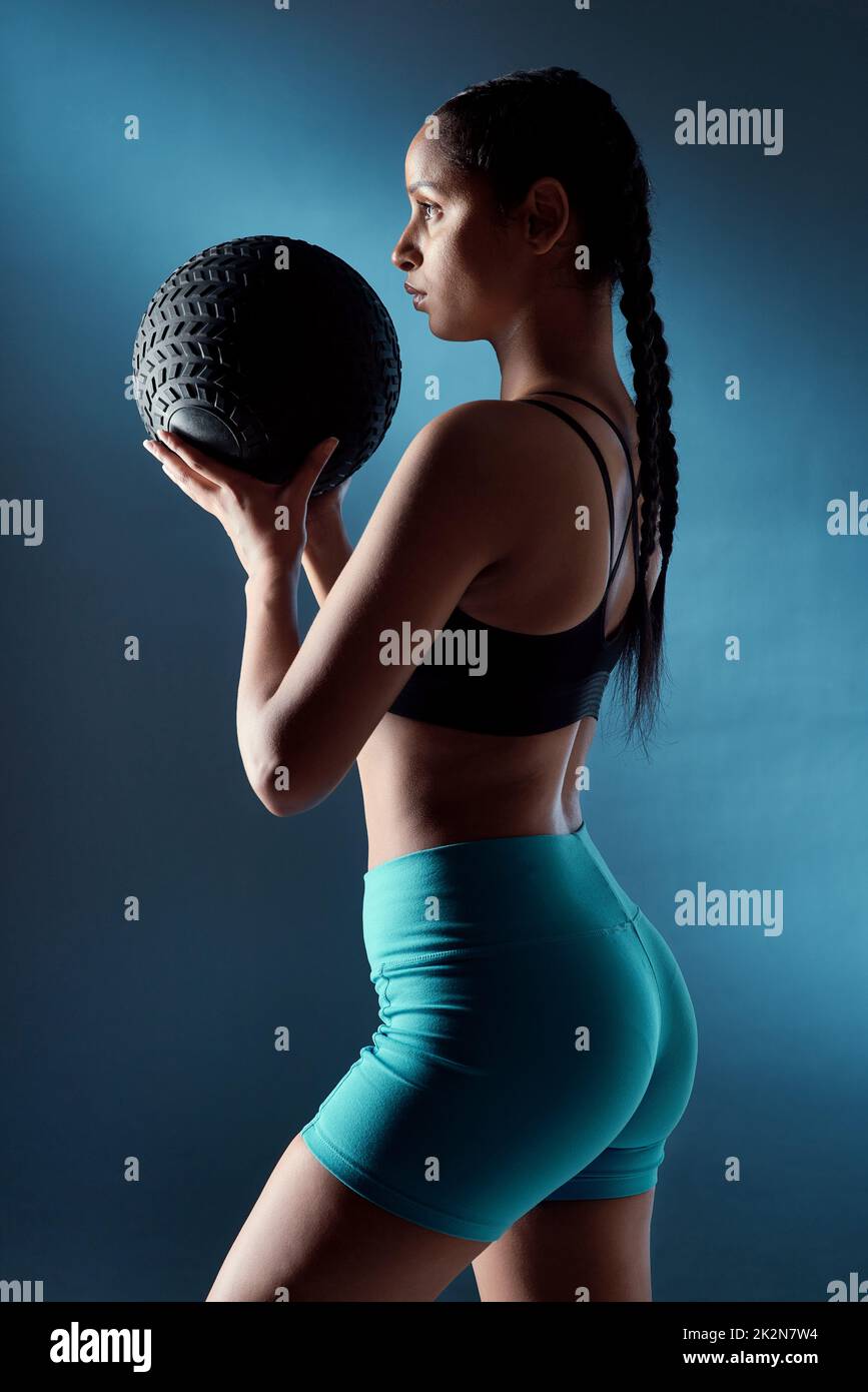 Warum launisch sein, wenn Sie Ihre Beute arbeiten können. Studioaufnahme einer sportlichen jungen Frau, die einen Übungsball vor blauem Hintergrund hält. Stockfoto