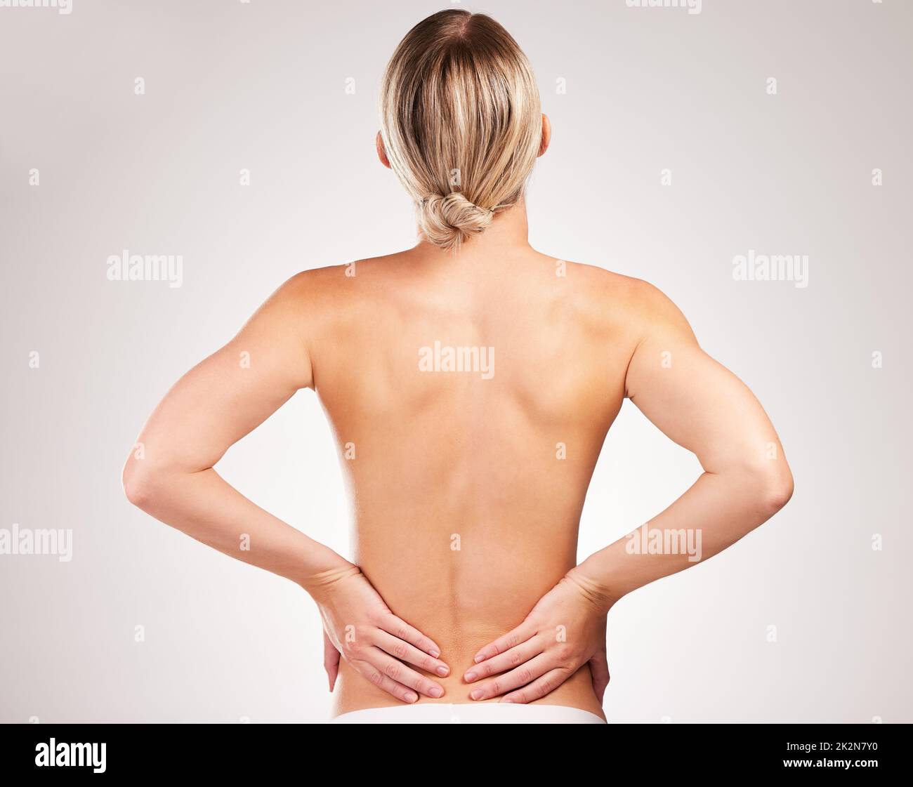 Der perfekte Körper nimmt Arbeit an. Studioaufnahme einer nicht erkennbaren jungen Frau, die mit dem Rücken vor grauem Hintergrund vor der Kamera posiert. Stockfoto