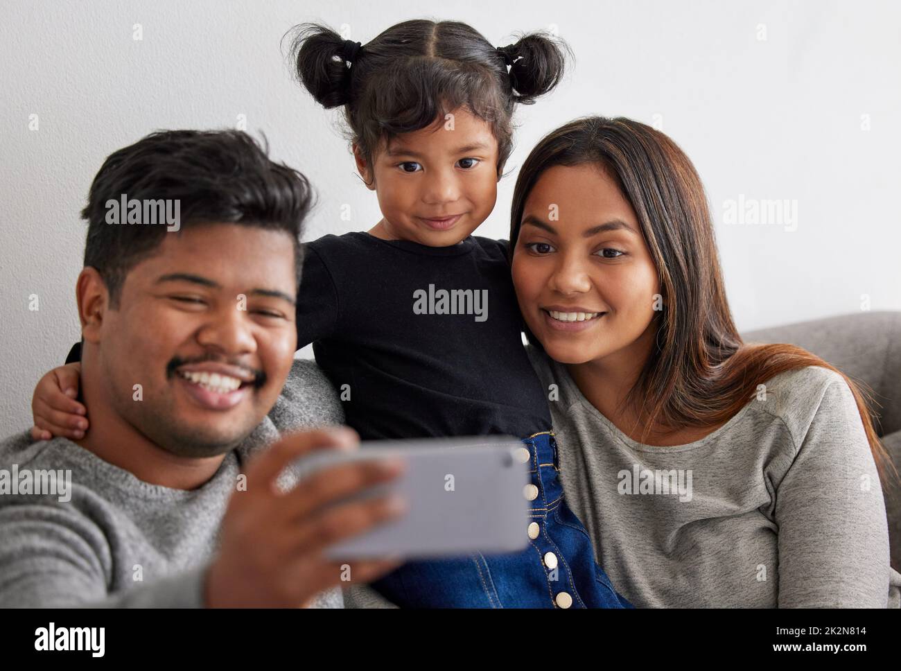 Erinnerungen zu machen, um immer ihr süßes Gesicht bei mir zu haben. Aufnahme von Eltern, die ein Selfie mit ihrer Tochter machen. Stockfoto