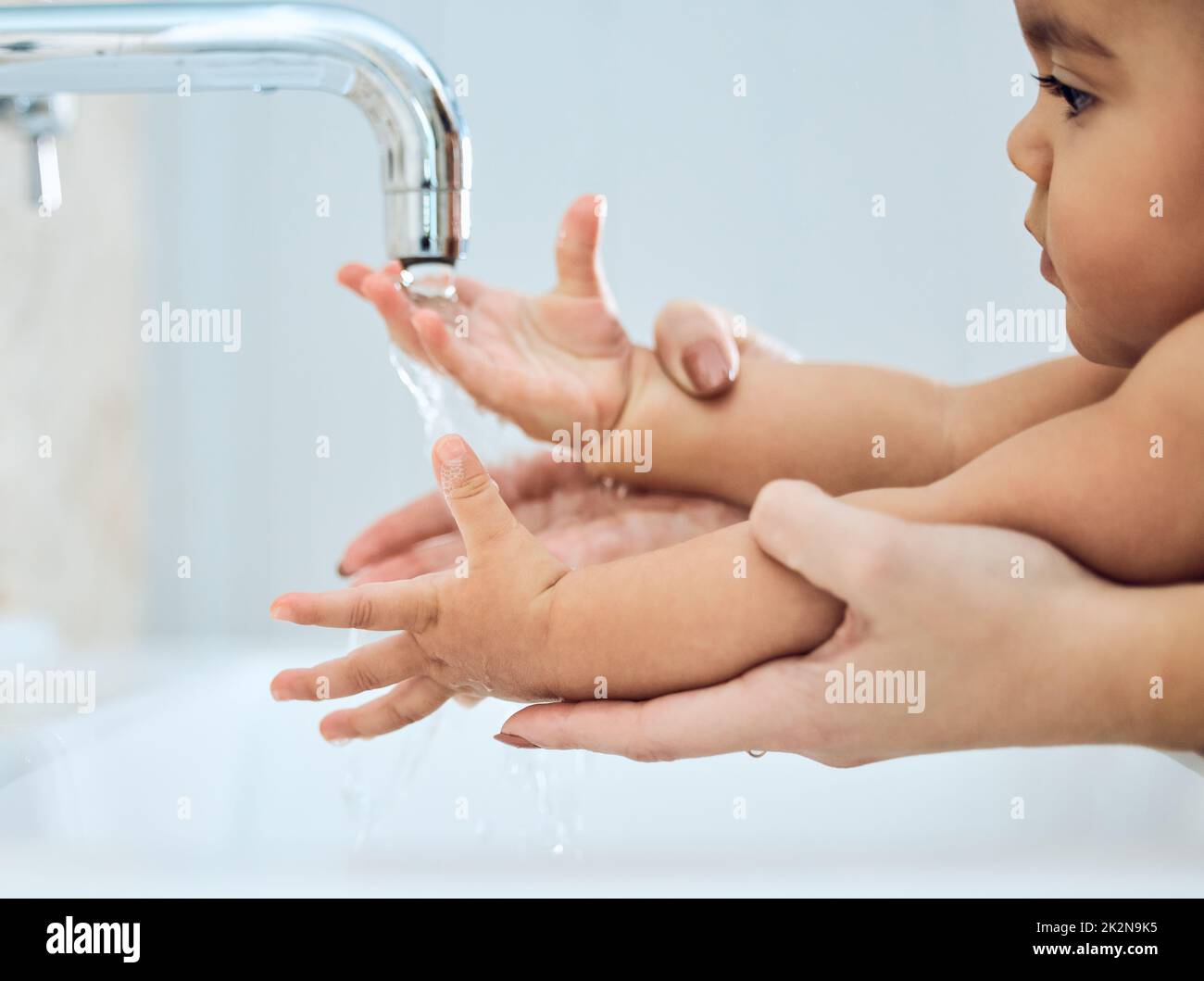 Ein glückliches und gesundes Baby aufziehen. Aufnahme einer Frau, die ihre Babys unter fließendem Wasser die Hände wäscht. Stockfoto