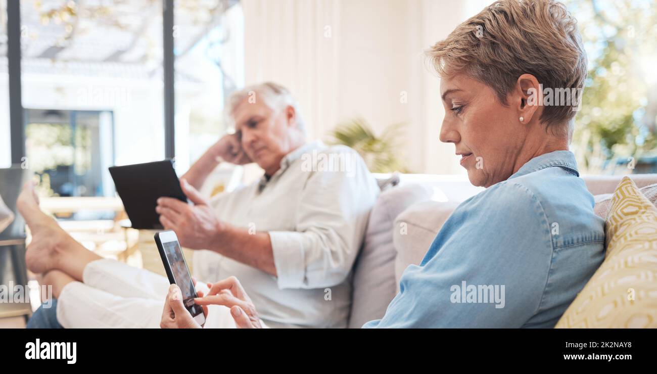 Entspannen Sie sich auf dem Sofa mit Smartphone- und Tablet-Technologie, um Filme anzusehen, während Sie sich über soziale Medien mit WiFi-Heimnetzwerk vernetzen. Ältere Frauen und Männer Stockfoto
