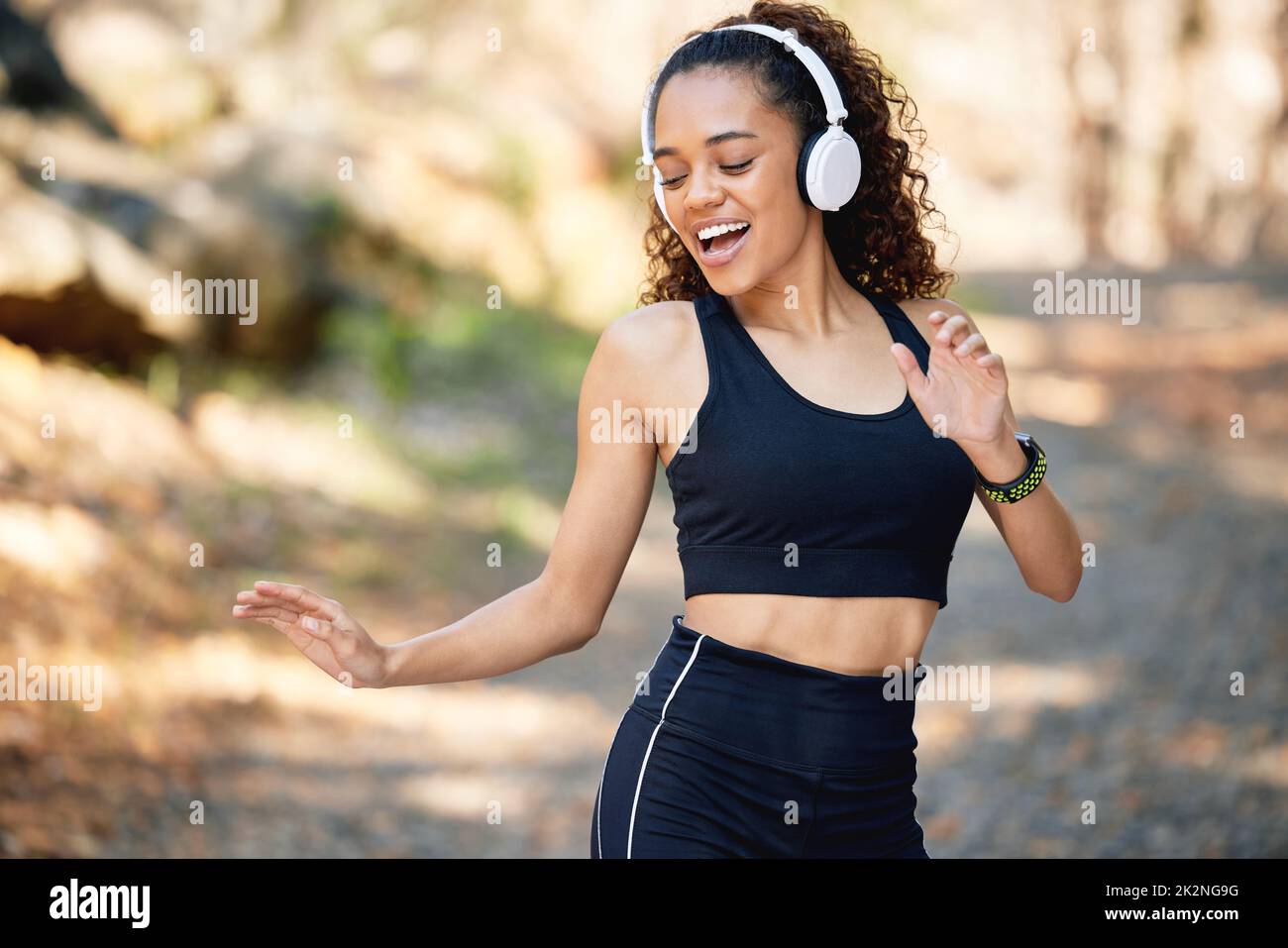 Übung kommt in vielen Formen. Aufnahme einer jungen Frau, die während eines Laufs zu fröhlicher Musik tanzt. Stockfoto