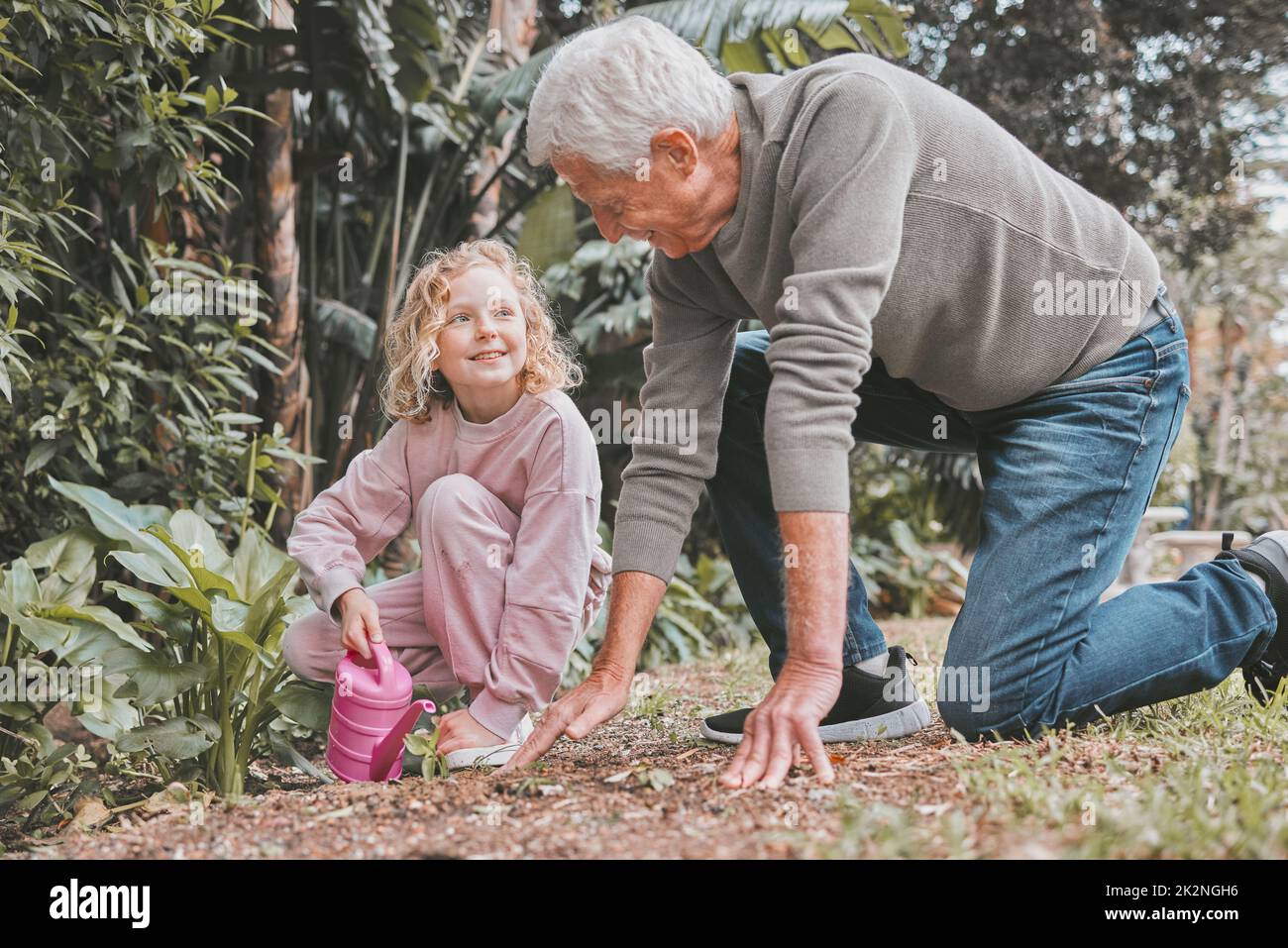 Der Schlamm wäscht sich weg, aber die Erinnerungen bleiben für immer bestehen. Aufnahme eines entzückenden kleinen Mädchens, das mit ihrem Großvater im Garten arbeitet. Stockfoto