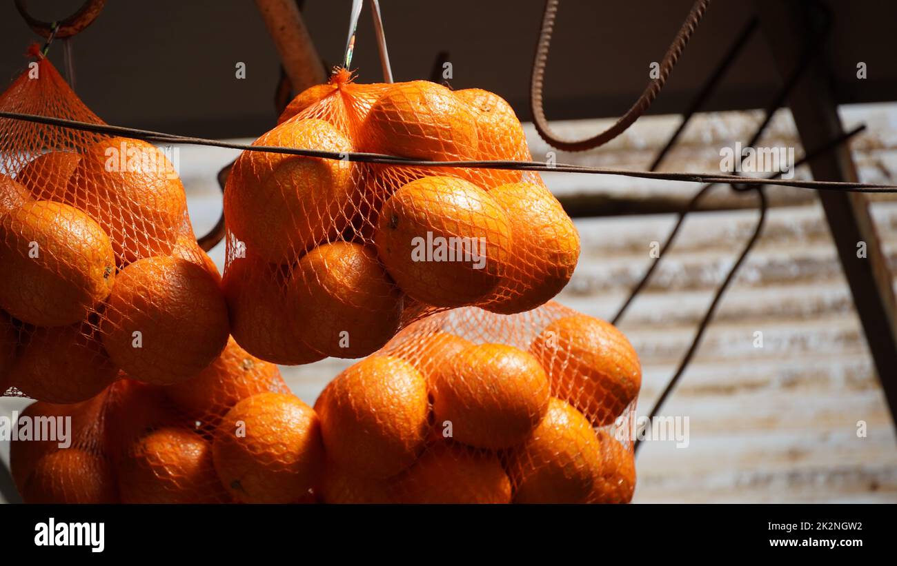 Haufen Orangen in roten Saitenbeuteln zum Verkauf auf dem lokalen Markt an einem Straßenstand in Nazareth, Israel Stockfoto