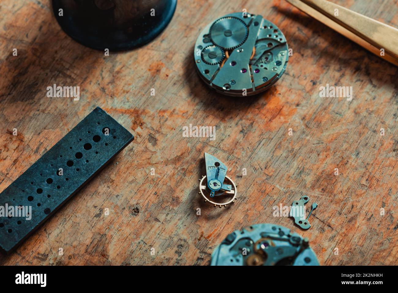 Zerlegte Uhr auf einer alten Werkbank des Uhrmachers Stockfoto