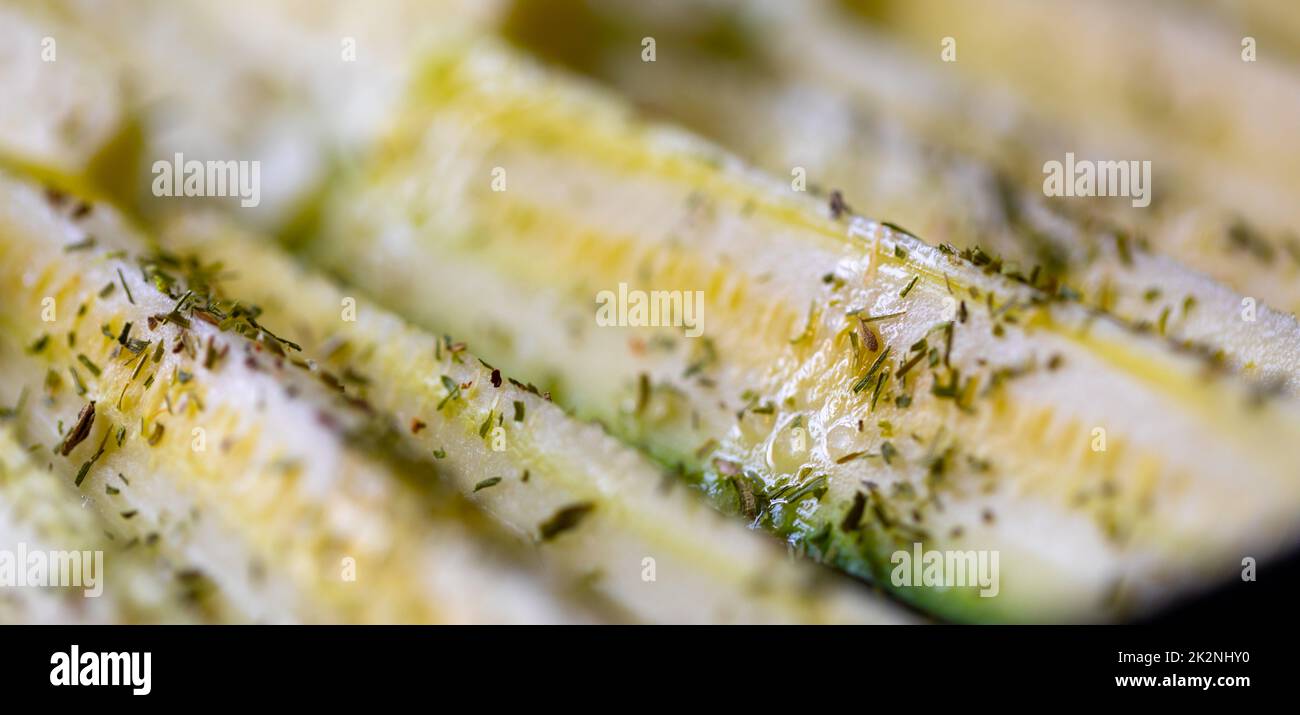 Frische Zucchini in Scheiben, gewürzt mit Kräutern Stockfoto