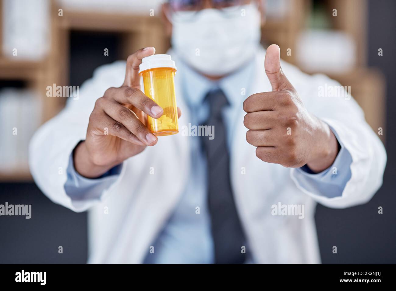 Dies wird das Problem lösen. Nahaufnahme eines nicht erkennbaren Arztes, der eine Flasche Pillen hält und Daumen in seinem Büro zeigt. Stockfoto