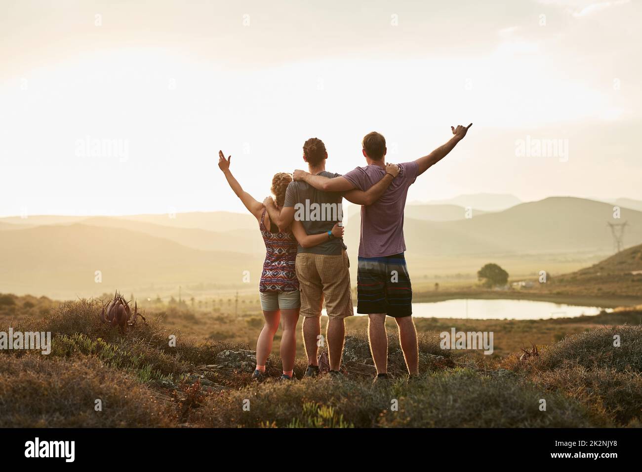 Jede Ansicht ist besser, wenn sie mit Freunden geteilt wird. Rückansicht von drei glücklichen Wanderern, die die Aussicht auf einen Bergpfad genießen. Stockfoto