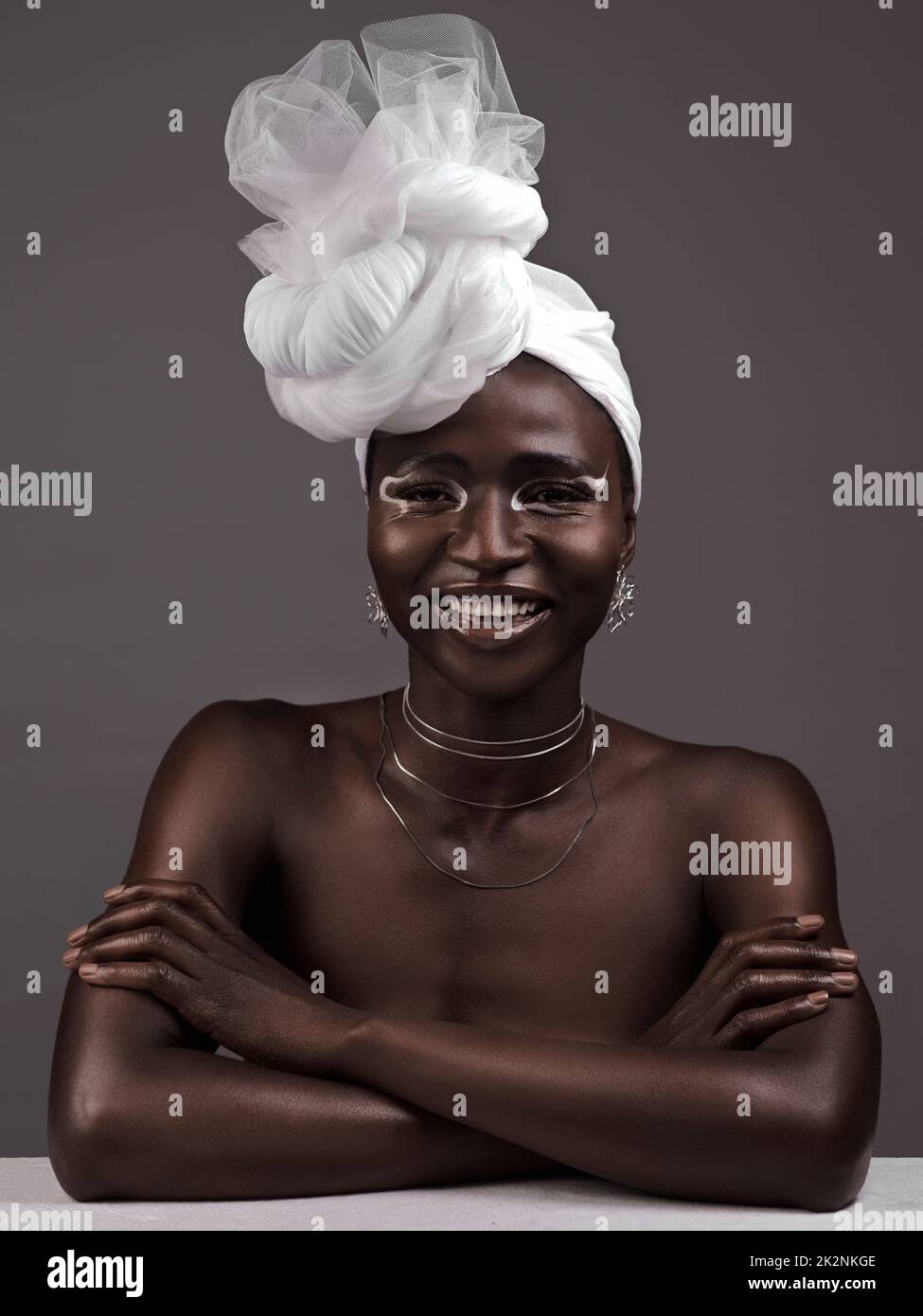Mehr als nur Stoff, es ist meine Krone. Studioporträt einer attraktiven jungen Frau, die in traditioneller afrikanischer Kleidung vor grauem Hintergrund posiert. Stockfoto