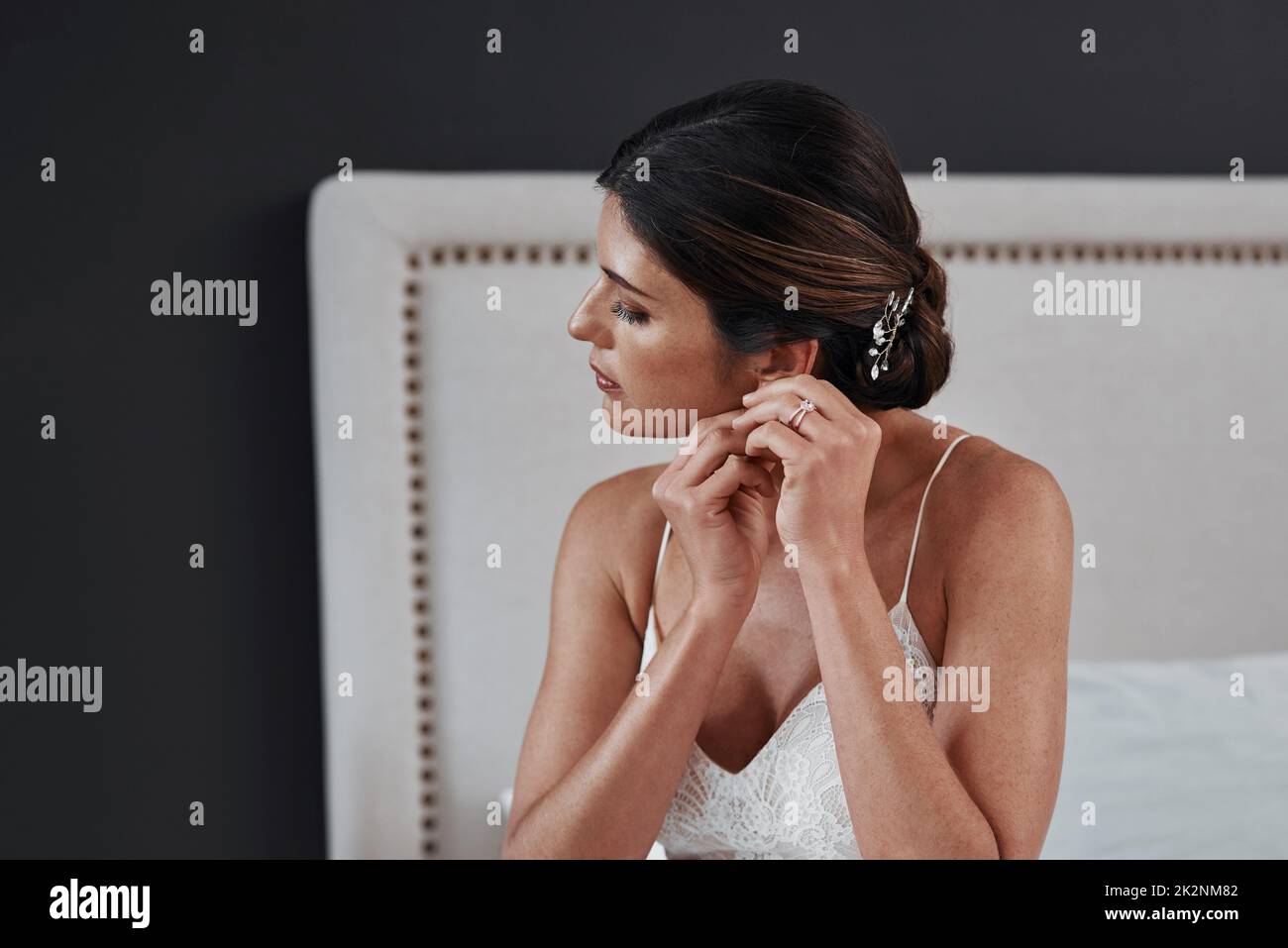 Diese Ohrringe sind etwas Neues für sie. Gekürzte Aufnahme einer attraktiven jungen Braut, die ihre Ohrringe anlegt, während sie sich für ihre Hochzeitszeremonie anzieht. Stockfoto
