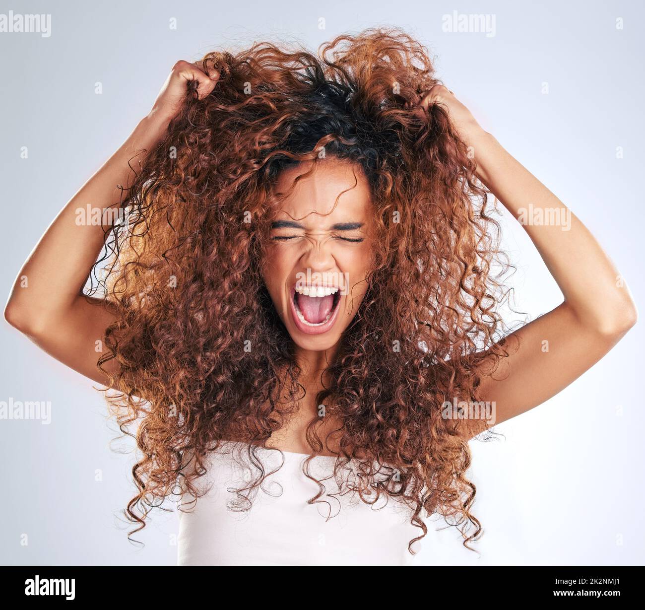 Das treibt mich in den Wahnsinn. Eine kurze Aufnahme einer attraktiven jungen Frau, die vor grauem Hintergrund frustriert im Studio aussieht. Stockfoto