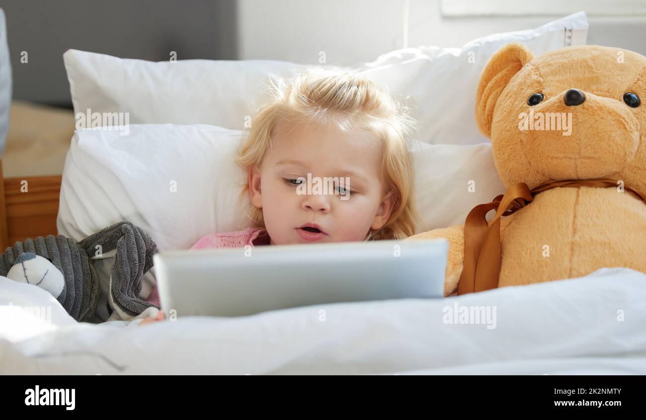 Ich kenne nur den Kinderreim zum Spielen. Aufnahme eines entzückenden kleinen Mädchens, das mit einem digitalen Tablet im Bett liegt. Stockfoto