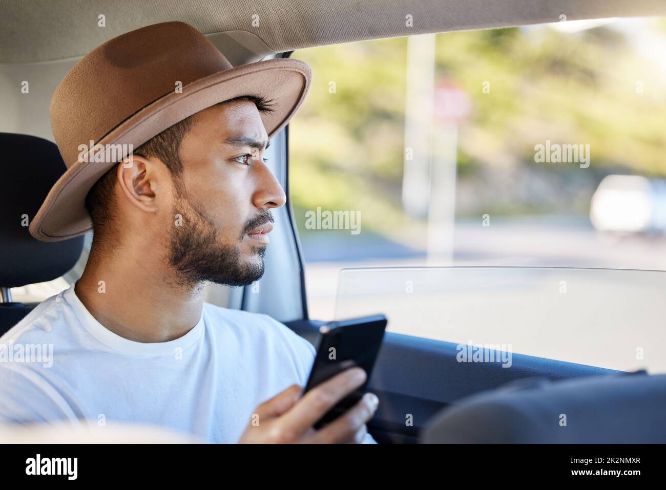 Es ist nicht das Ziel, es ist die Reise. Aufnahme eines jungen Mannes, der in einem Auto sitzt, während er sein Telefon benutzt. Stockfoto