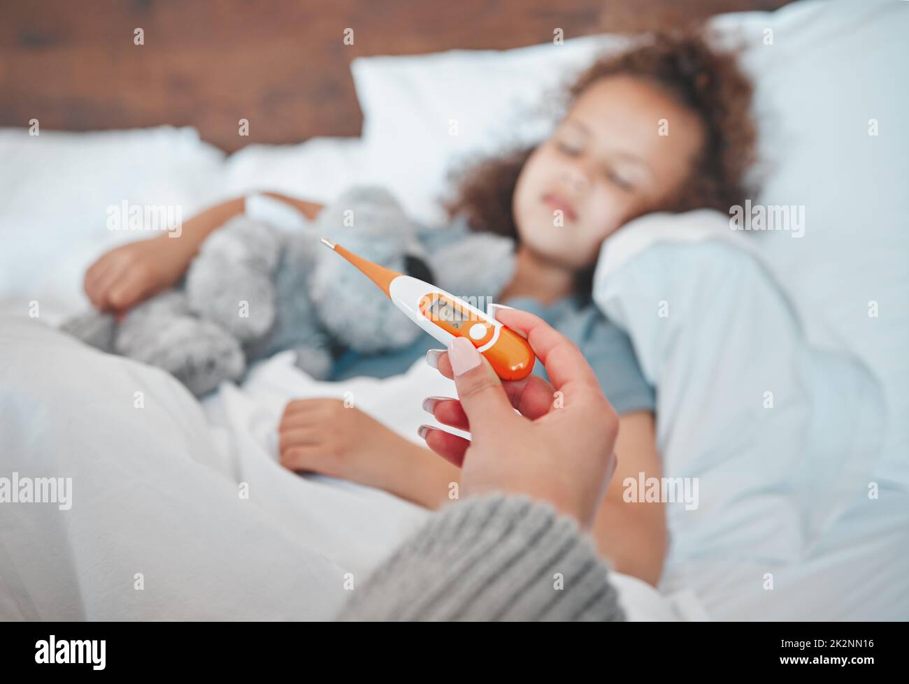 Bekämpft das Fieber. Aufnahme eines unverkennbaren Elternteils, der die Temperatur seiner kranken Kinder zu Hause einnahm. Stockfoto