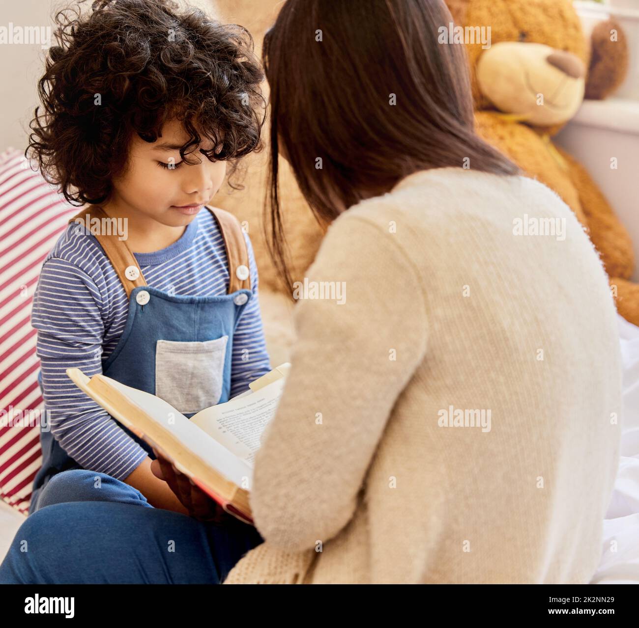 Dies ist seine Lieblingsgeschichte. Aufnahme eines kleinen Jungen und seiner Mutter, die zu Hause zusammen lesen. Stockfoto