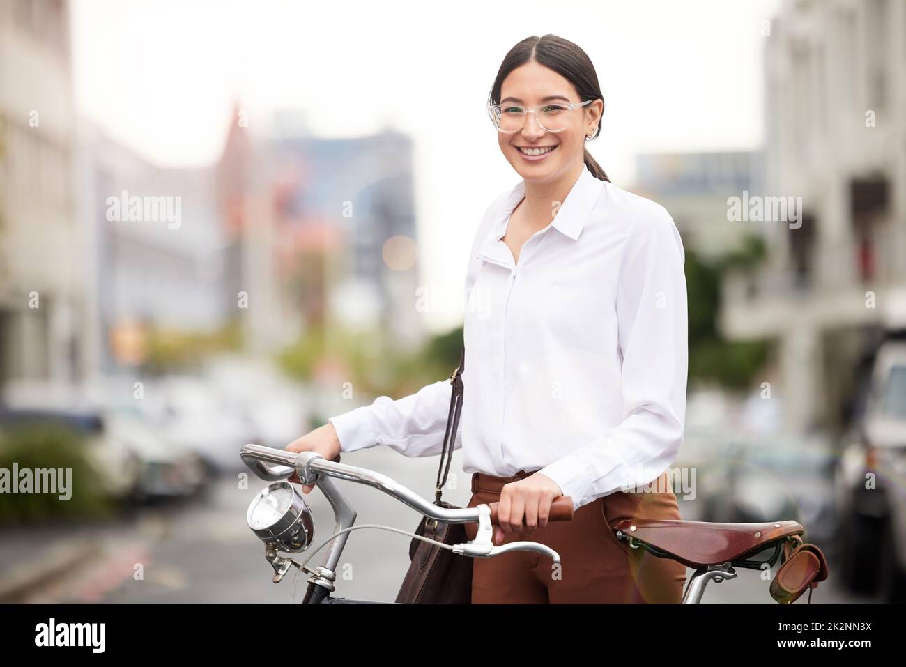Sie leistet ihren Beitrag zur Reduzierung von Luftschadstoffen. Porträt einer jungen Frau, die mit ihrem Fahrrad die Stadt erkundet. Stockfoto