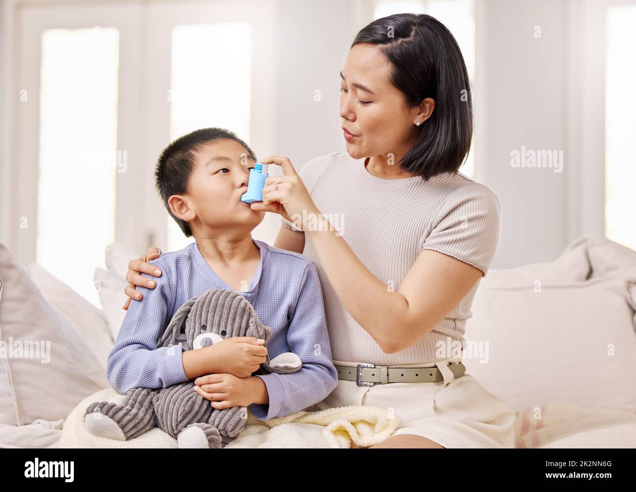 Atmen Sie langsam ein. Aufnahme einer Frau, die ihrem Sohn mit seinem Asthmainhalator half. Stockfoto