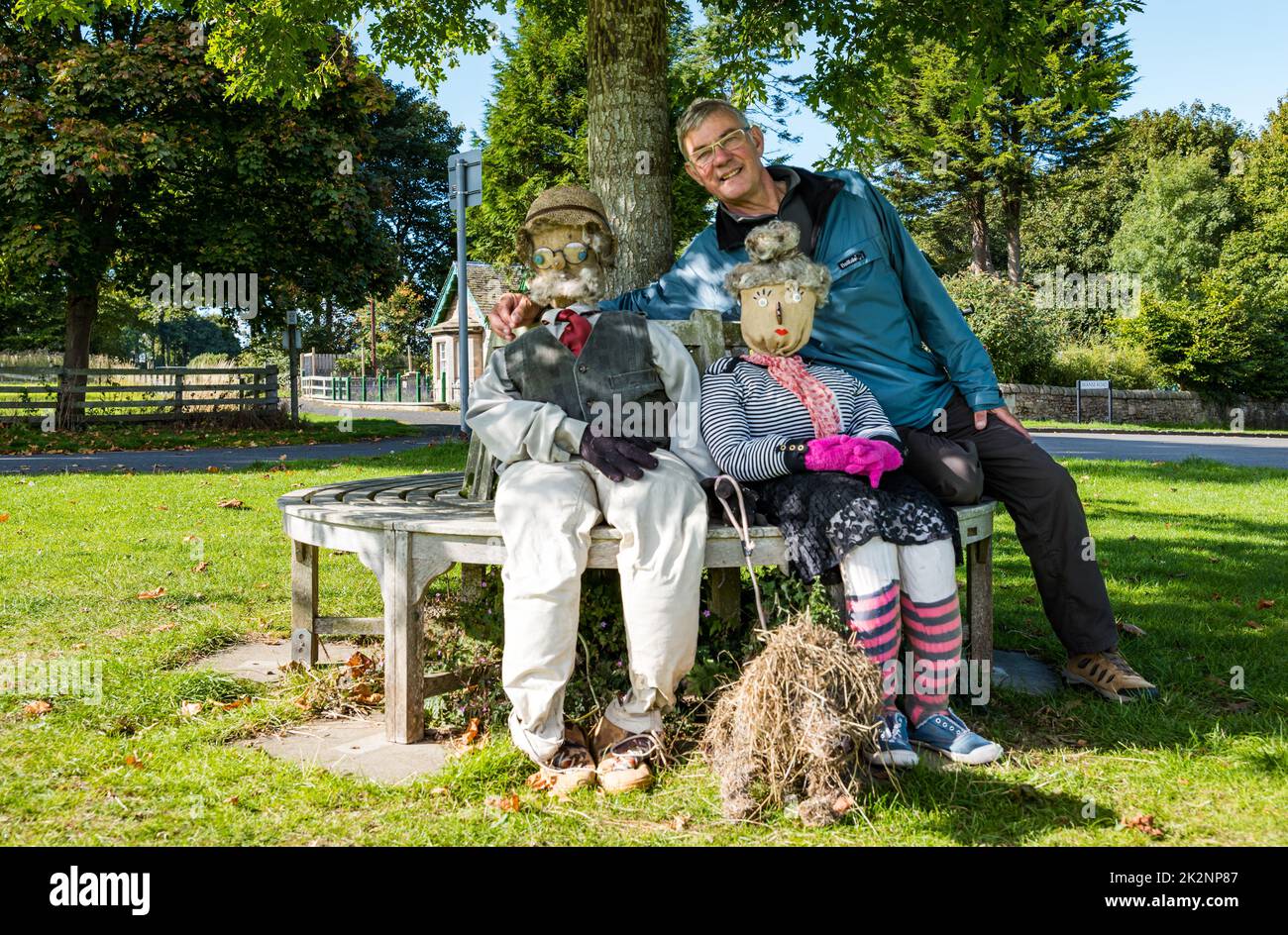 Dirleton, East Lothian, Schottland, Großbritannien, 23.. September 2022. Scarecrow Trail: Der zweite Trail in diesem Jahr hat 18 Vogelscheuchen rund um das Dorf. Im Bild: Ein Mann, der mit ein paar fabelhaften Vogelscheuchen auf dem Dorfgrün sitzt. Kredit: Sally Anderson/Alamy Live Nachrichten Stockfoto