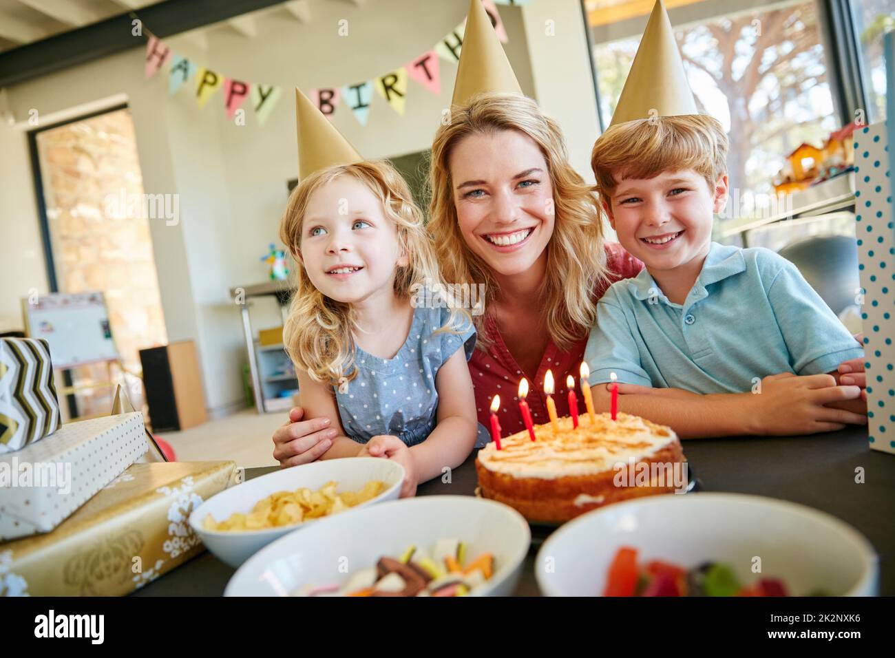 Dies sind die Momente, die man schätzen muss. Porträt einer Mutter und ihrer beiden Kinder, die zu Hause eine Geburtstagsfeier feiern. Stockfoto