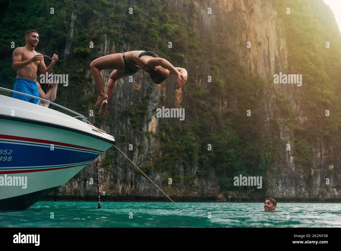 Kein Risiko, keine Belohnung. Aufnahme einer jungen Frau, die einen Rückschlag von einem Boot macht, während ihre Freunde zusehen. Stockfoto