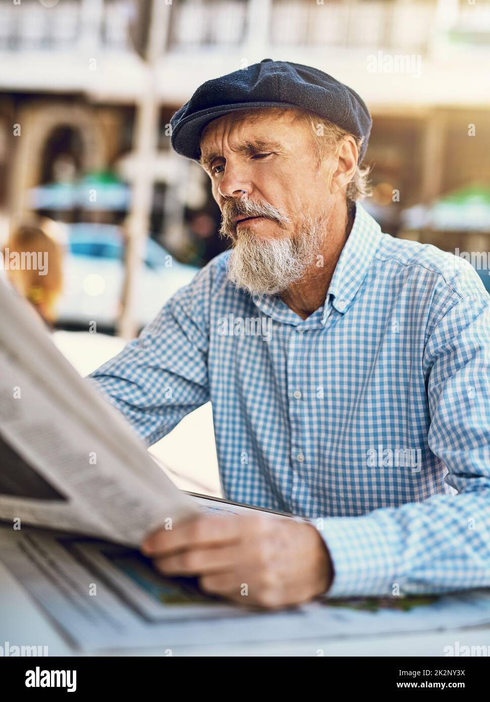 Was heute in der Welt passiert. Aufnahme eines ernsthaften älteren Mannes, der die Zeitung las, während er in einem Straßencafé saß. Stockfoto