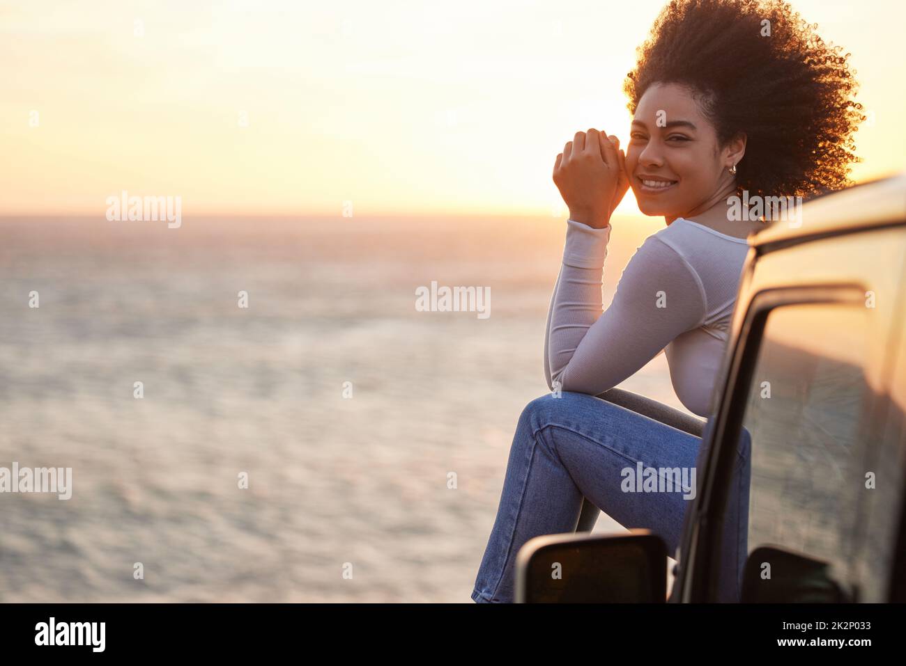 Dies ist mein heimlicher, glücklicher Ort. Porträt einer jungen Frau, die die frische Strandluft genießt, während die Sonne untergeht. Stockfoto