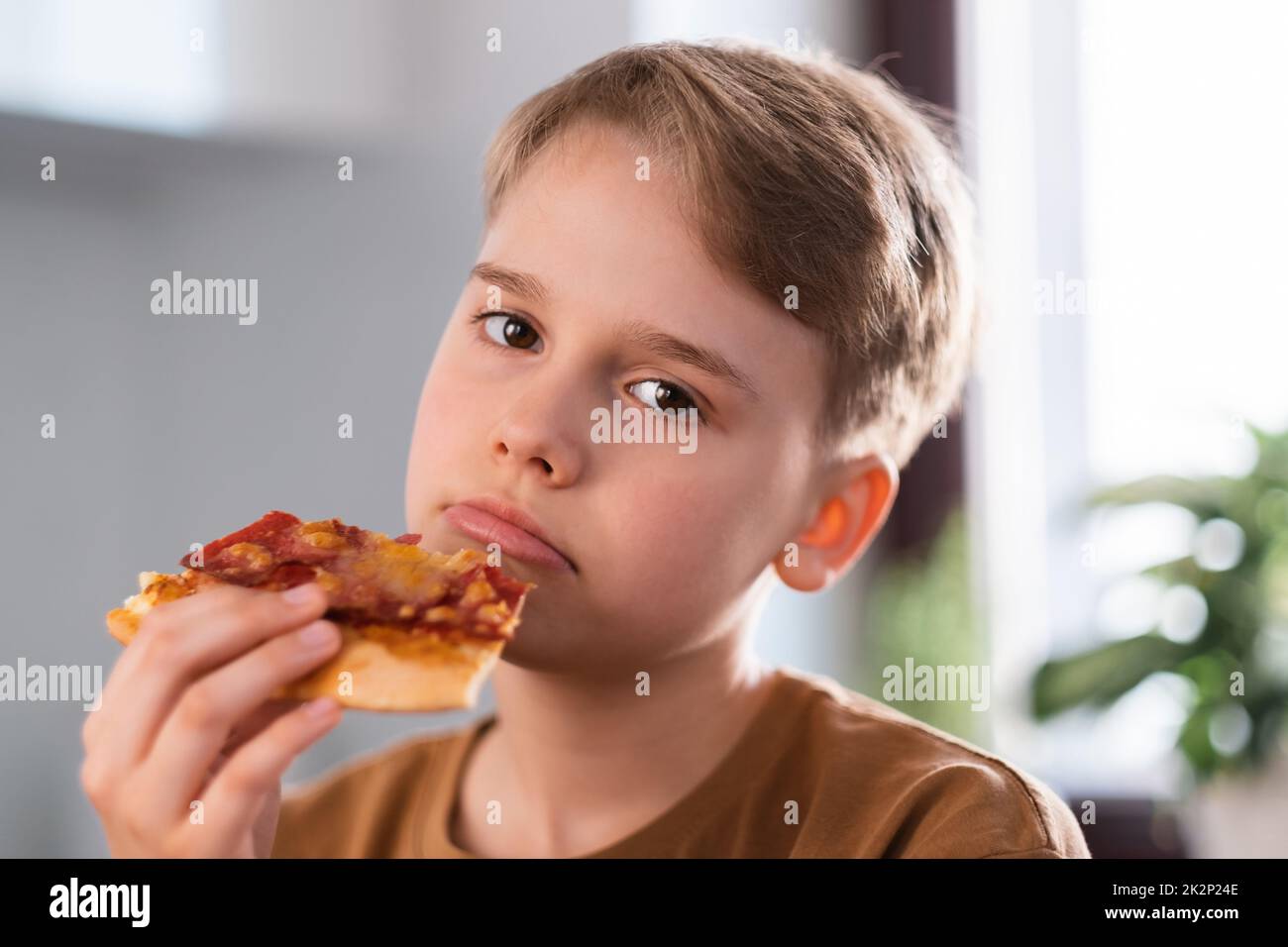 Trauriger Teenager Junge genießt zu Hause köstliche Pizza zu essen. Stockfoto