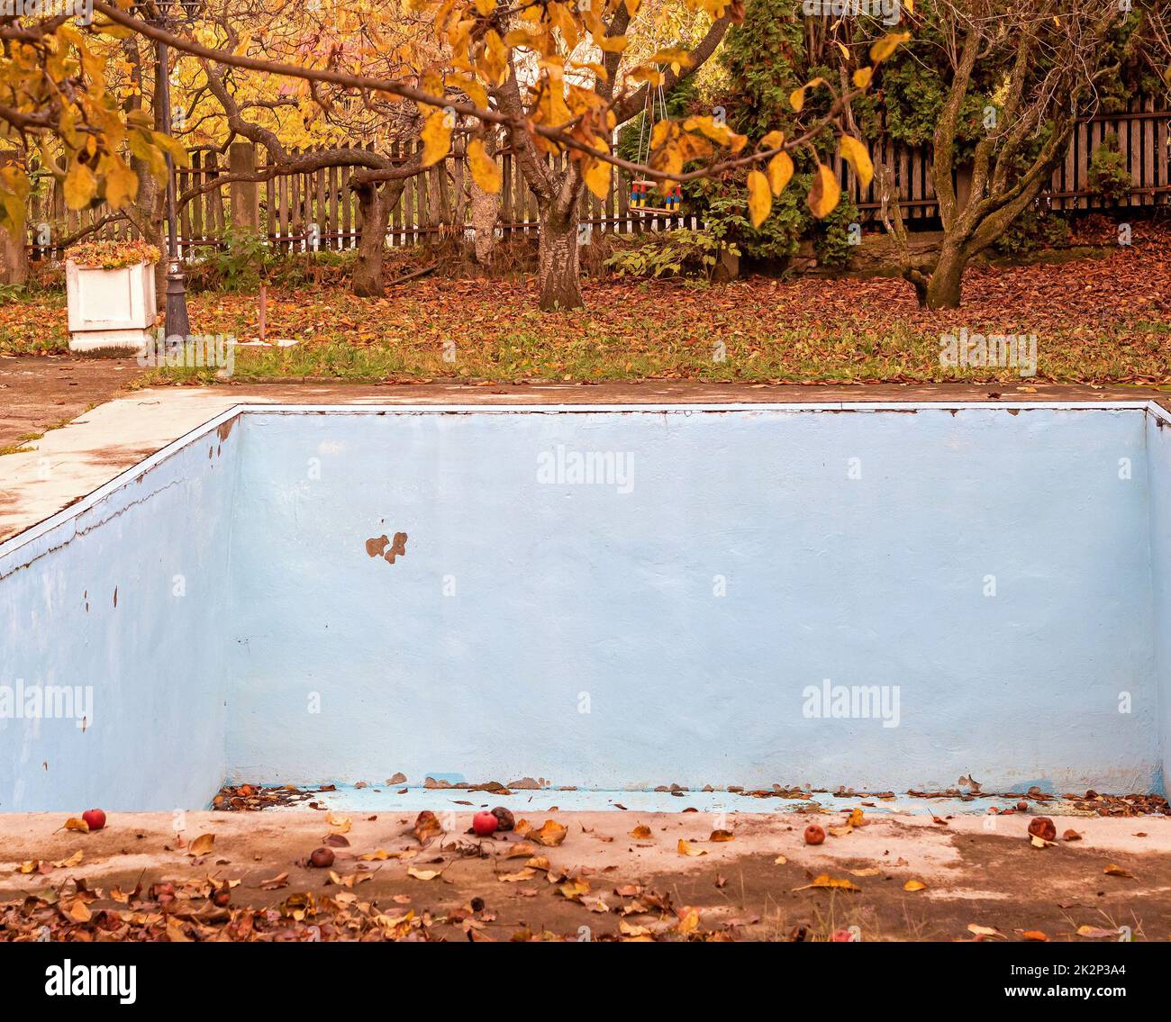 Leerer Swimmingpool mit trockenen Blättern auf dem Boden Stockfoto