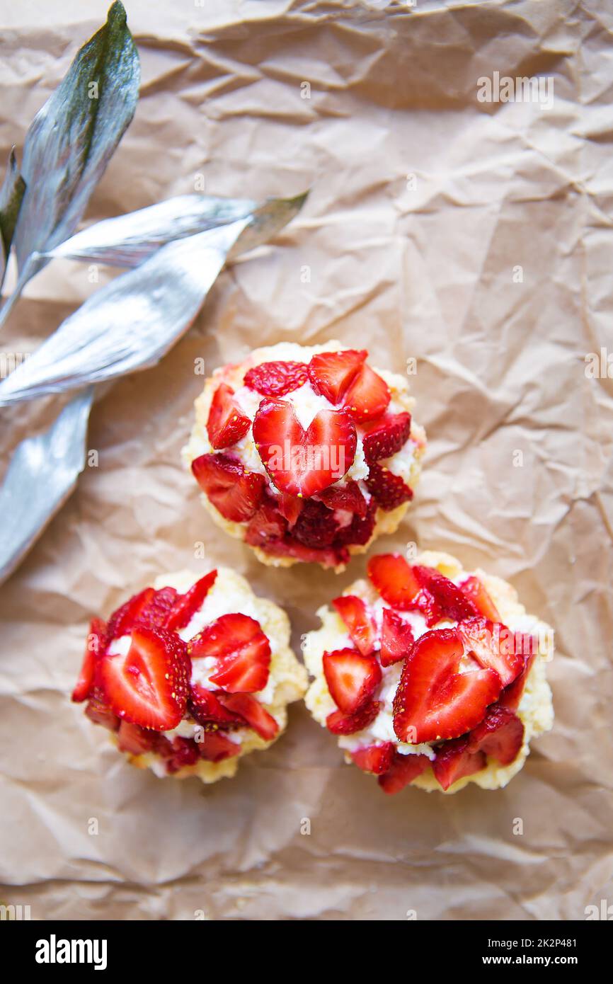 Schöne kleine Kuchen mit Erdbeeren zusammen mit einem Zweig auf Kraftpapier Stockfoto