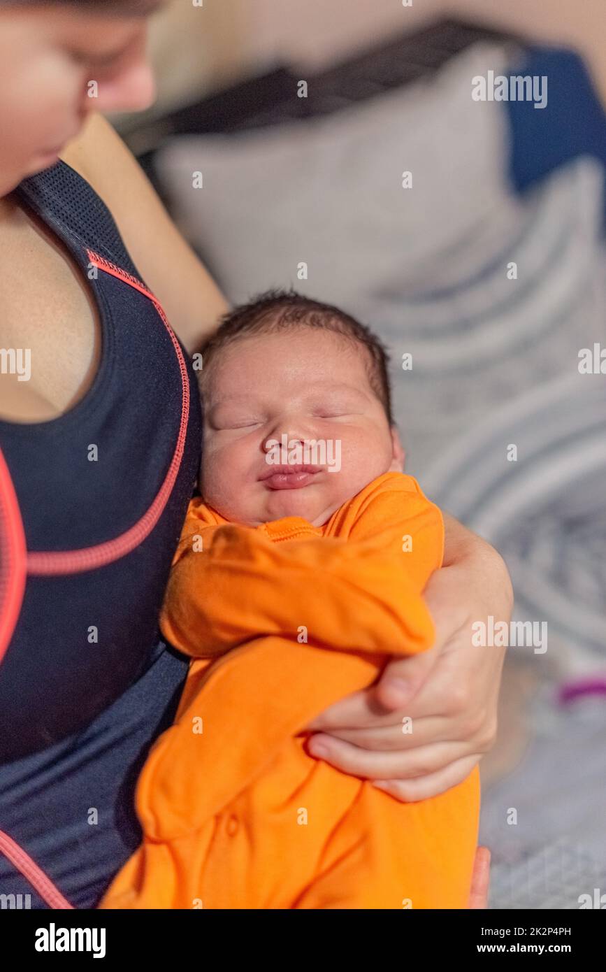 Die junge Mutter hält ihr schlafendes Neugeborenes in den Armen Stockfoto