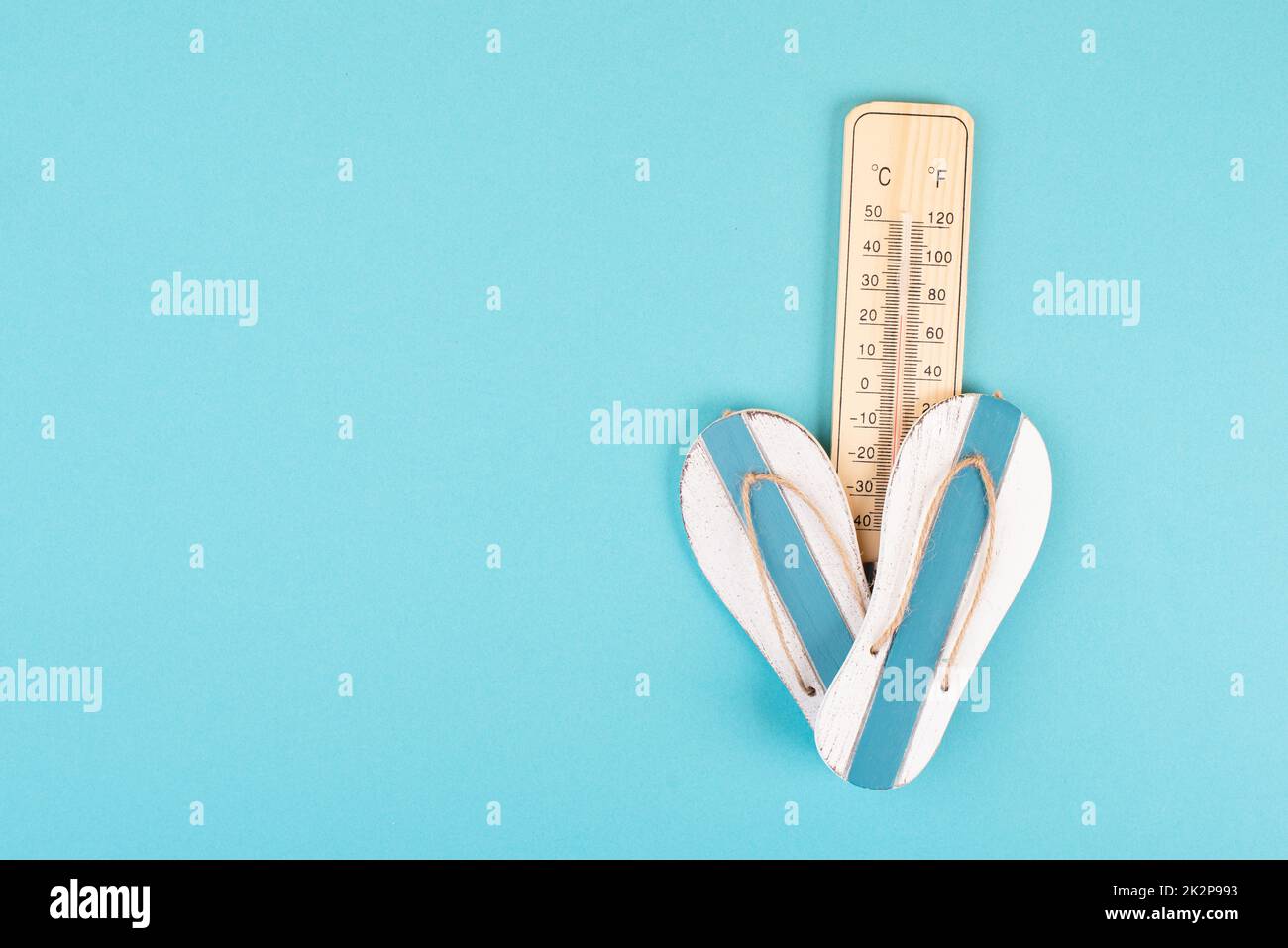 Leerer blauer Hintergrund mit Thermometer und Flip Flops, Urlaubshintergrund, Sommerurlaub, heißes Wetter, Strandartikel Stockfoto