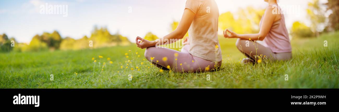 Zwei Frauen sitzen in aktiver Kleidung in Lotusposition in der Natur. Stockfoto