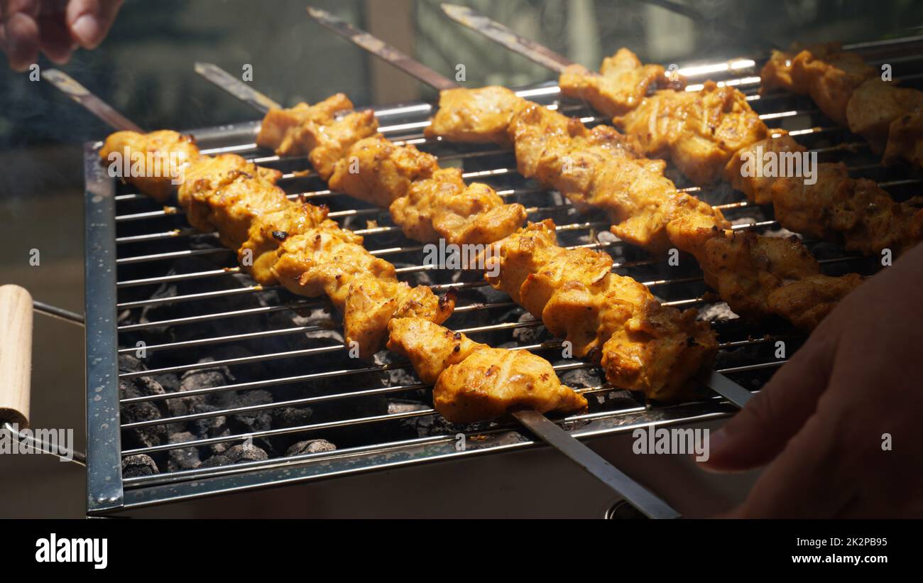 Shashlik: Traditionelles georgianisches Barbecue. Nahaufnahme von roh geröstetem mariniertem Fleisch Barbecue Shish Kebab Shashlik auf Stahlspießen liegend Grill Feuerlöscher mit Holzkohle. Ich mache Barbecue Stockfoto