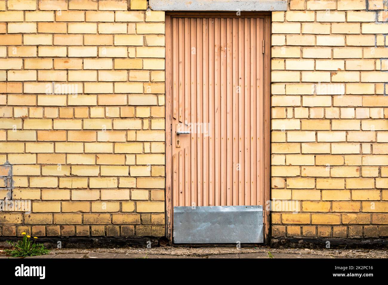 Alte Holztür an einer gelben Ziegelwand Stockfoto