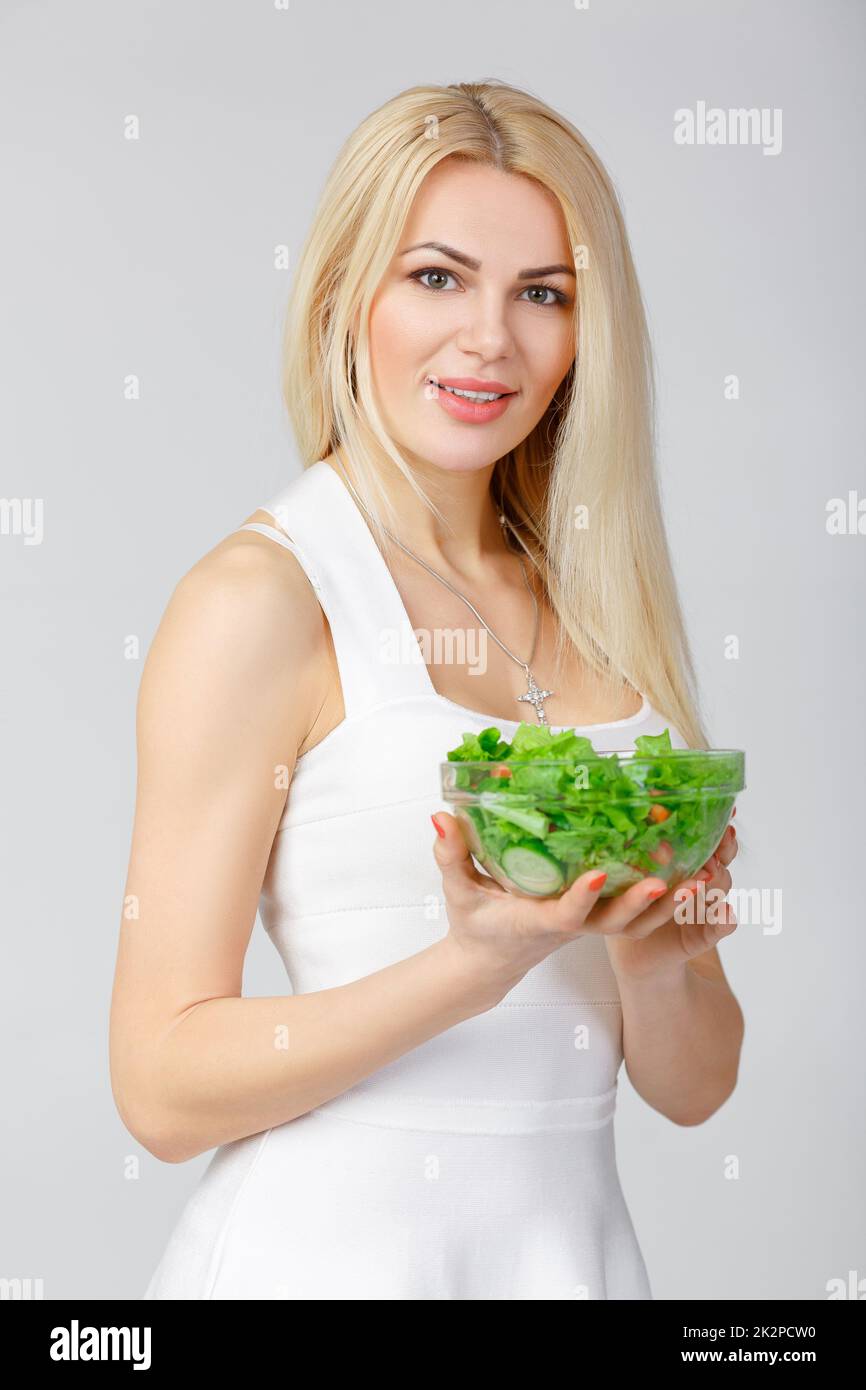 Frau in weißem Kleid mit frischem Salat Stockfoto