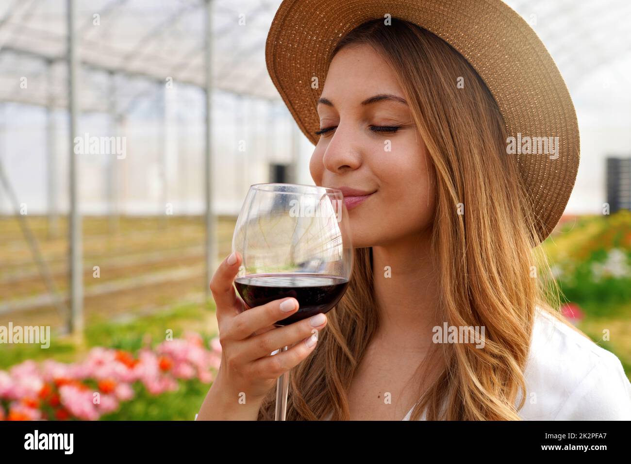Nahaufnahme einer schönen Frau, die mit geschlossenen Augen Rotwein aus dem Glas riecht Stockfoto
