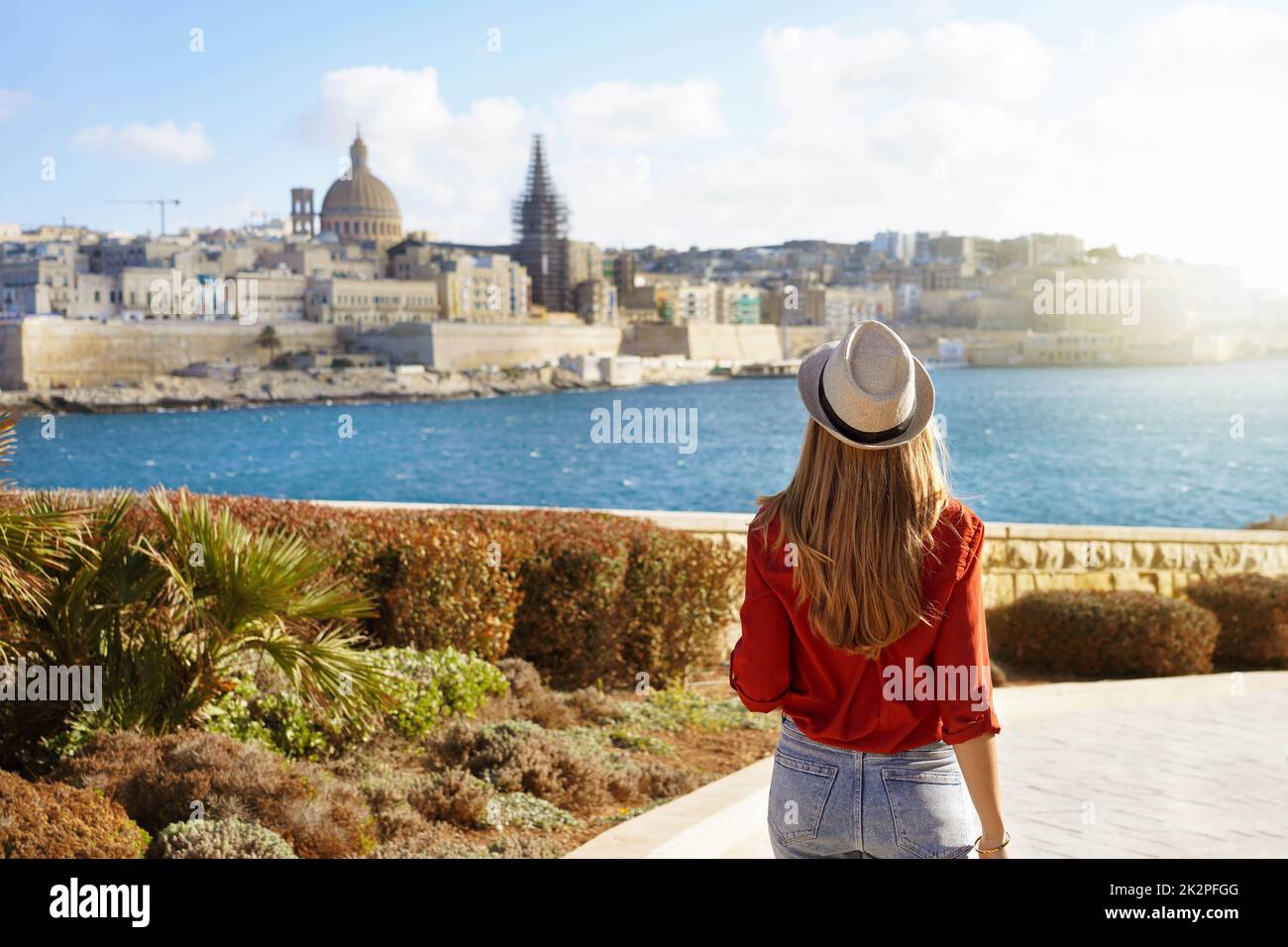 Attraktive Frau mit Hut geht entlang Malta Waterfront Blick auf die schöne Stadtlandschaft von Valletta, Malta Stockfoto