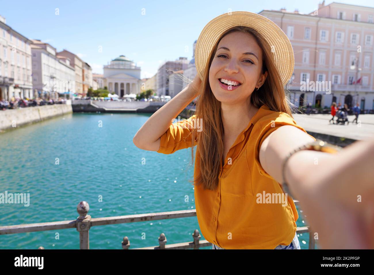 Junge Touristenfrau macht Selfie-Foto auf der Brücke mit schöner Aussicht auf Triest Stadt in Italien Stockfoto