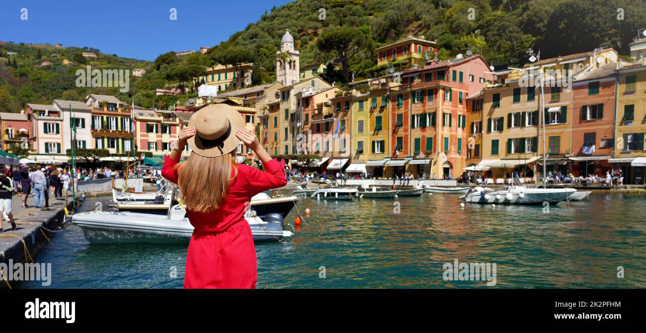 Urlaub in Portofino, Italien. Rückblick auf ein wunderschönes Mädchen in rotem Kleid mit Blick auf das malerische Dorf Portofino mit festgefahrenen Schiffen und Menschen, die auf dem Piazzetta Platz spazieren, Panoramabanner. Stockfoto