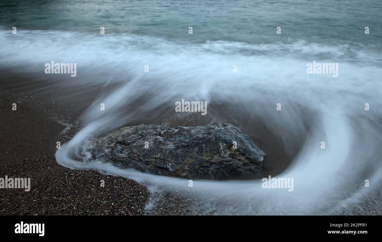Wunderschöne Langzeitaufnahme der Meereslandschaft, seidig glatte Meereswelle, die am Felsen vorbeizieht Stockfoto