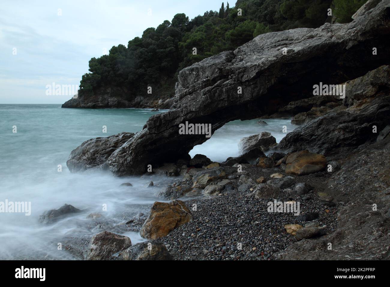 Glatte Meereswellen am natürlichen Steinbogen bei Lerici, Italien Stockfoto