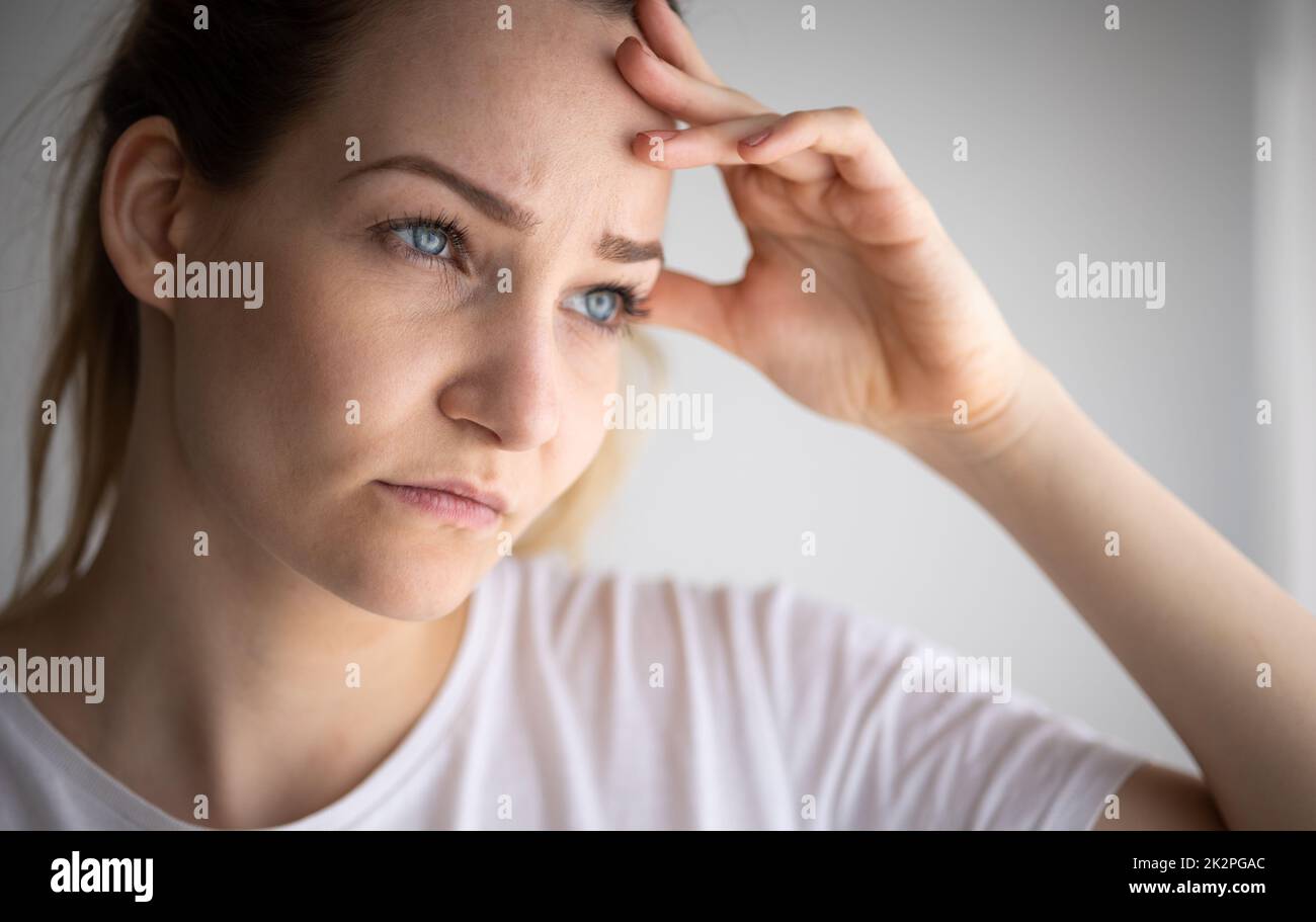 Ängstlich, besorgt, gestresste junge Frau, die nachdenklich, nachdenklich, tief in Gedanken aussieht. Stockfoto