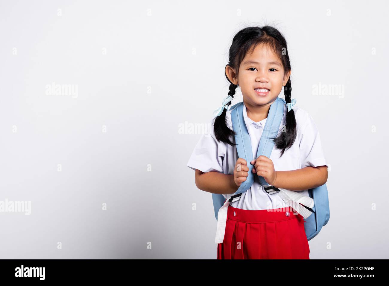 Asiatische liebenswert Kleinkind lächelnd glücklich tragen Student thai uniform roten Rock stehen Stockfoto
