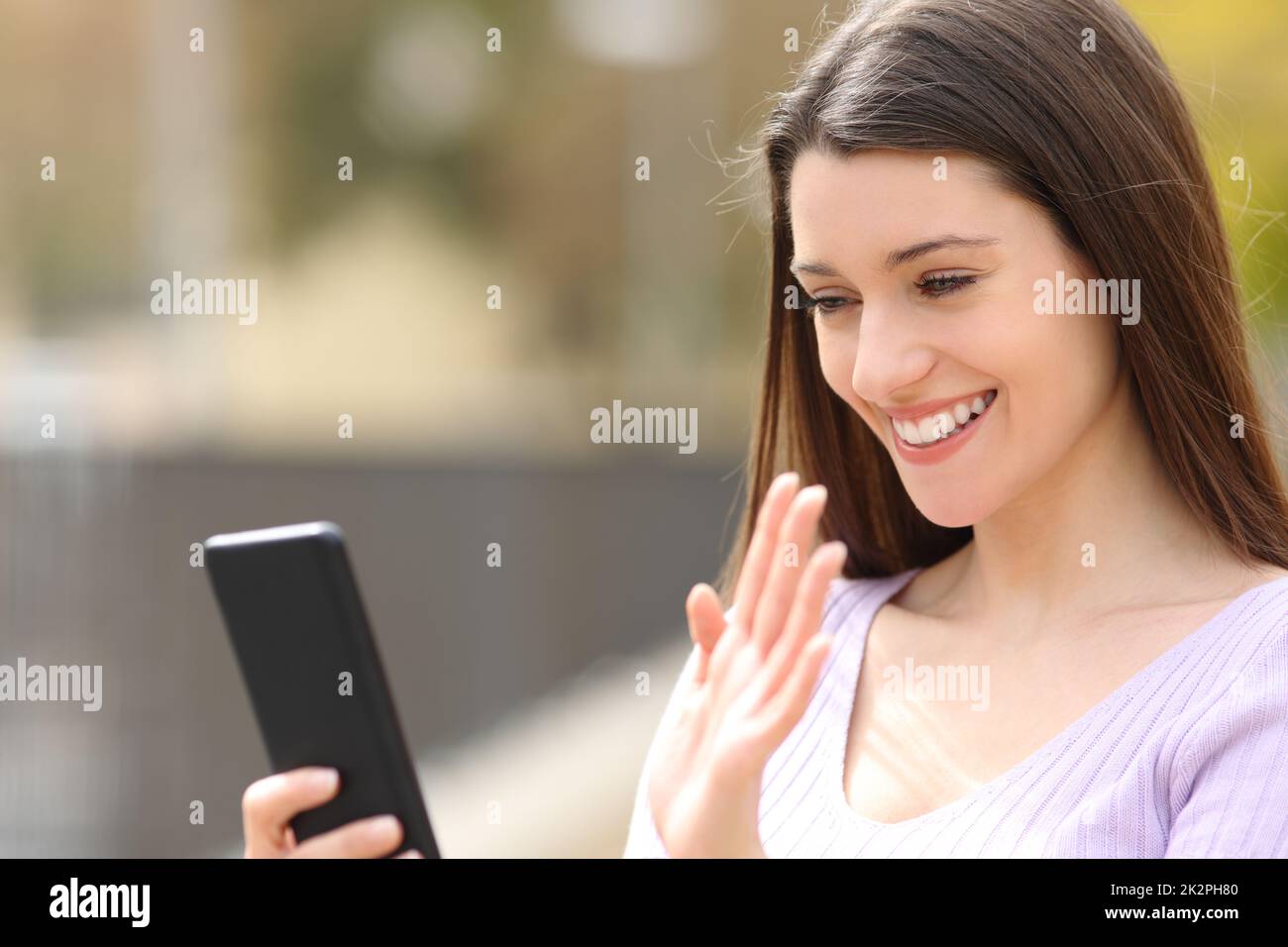 Glückliche Frau, die während eines Videogesprächs am Telefon grüßt Stockfoto