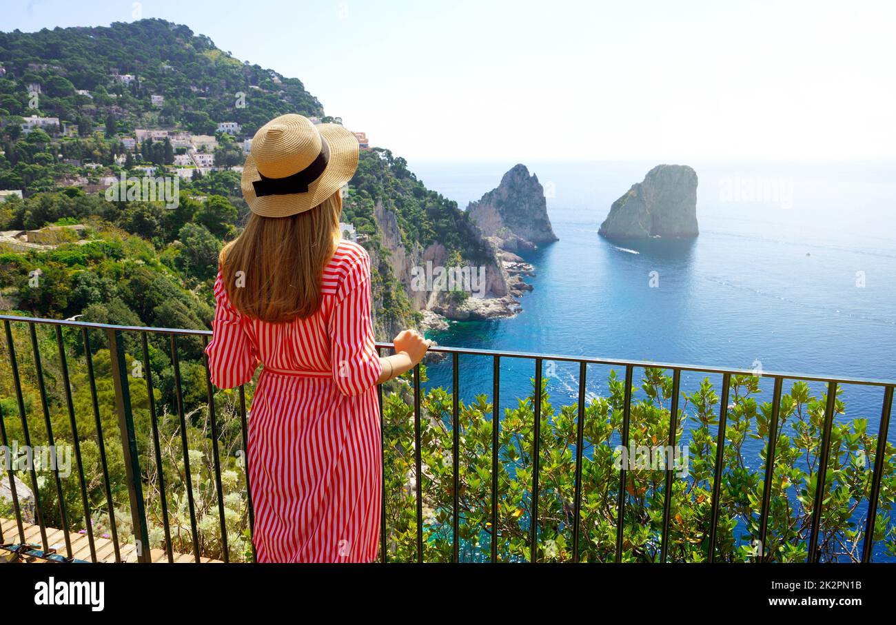 Urlaub in Italien. Rückansicht eines wunderschönen Mädchens auf der atemberaubenden Insel Capri mit Faraglioni-Meer und blauem kristallklarem Wasser im Hintergrund, Capri, Italien. Stockfoto